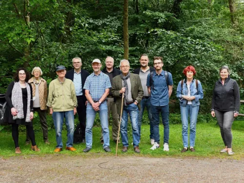 Mehrere Personen auf einer Gr&uuml;nfl&auml;che im Wald.